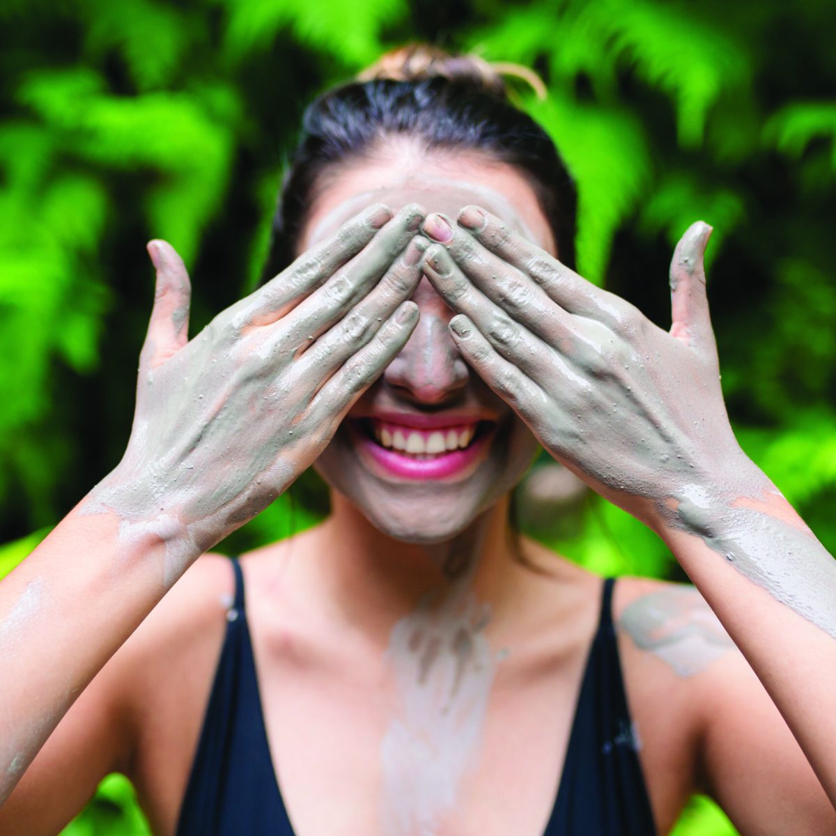 lodo1 a women covering both eyes with muddy hands from the baths