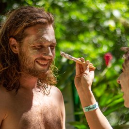 a women painting a mans face with mud