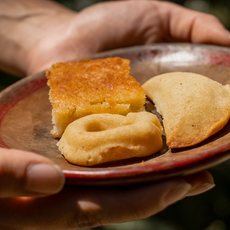 a hand holding a piece of bread on a plate