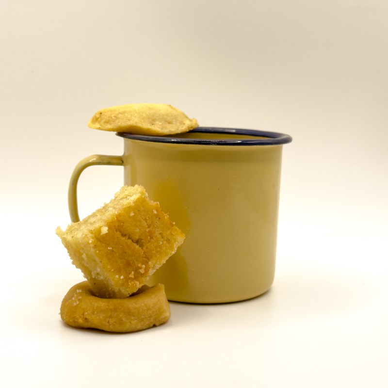 Yellow mug with a cookie on top and two cookies leaning against it.