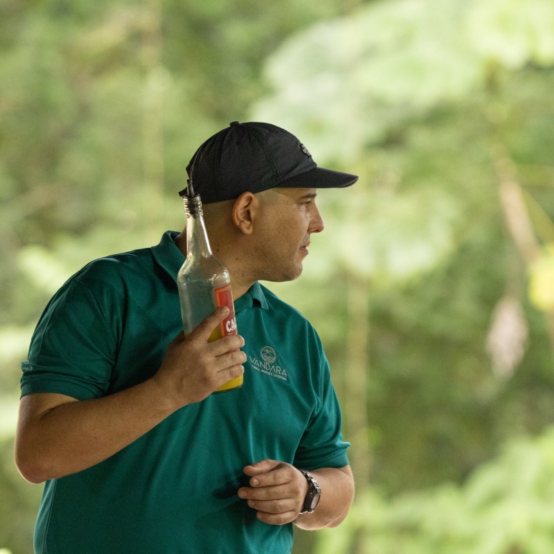 Person in teal shirt and cap holding a clear bottle, outdoors.